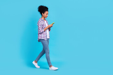 Full length photo of pretty cheerful girl dressed checkered shirt typing apple samsung iphone empty...