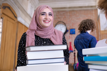 Beautiful International Emirati Student at library with books in the front. Arab in Hijab with...