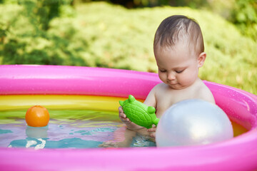 cute baby girl swimming in kid inflatable pool