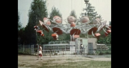 Carousel spins in amusement park in sunny summer. Carnival attraction in park festival. Holiday entertainment outdoors. Archival vintage color film. Archive lifestyle video. Retro 1980s Moscow Russia