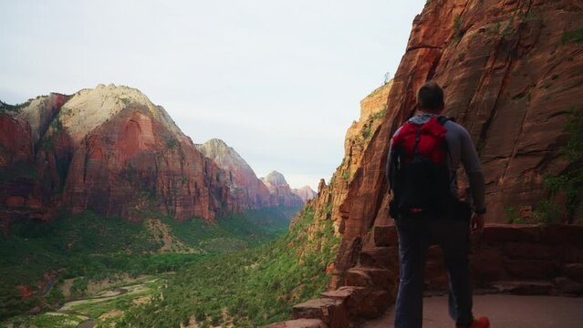 Person hiking in Angels Landing in Zion national park in Utah with huge cliffs