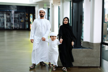 Walking Emirati Arab Family indoors, hotel or shopping mall concept. Middle Eastern husband, wife...