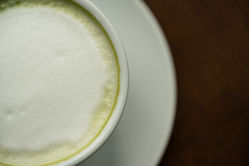 Top view white cup of hot green tea latte on wood background in restaurant.Top view with copyspace for your text.