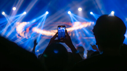 People holding smart phone and recording and photographing in concert , silhouette of hands with...