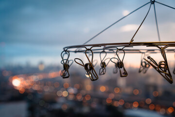 Close up of stainless steel hanging clothespins with blurred background of city in rainy day