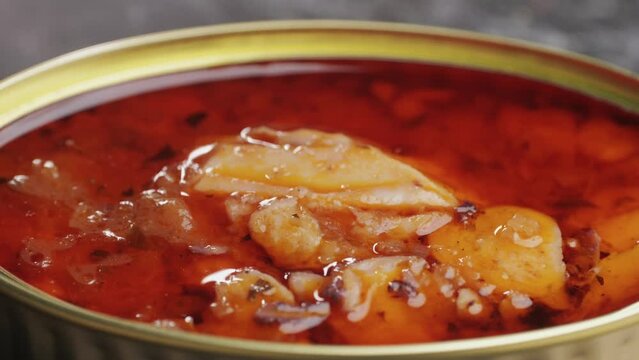 Opening canned octopus squid fish can, man open the canned seafood on the table. Close up on professional kitchen.
