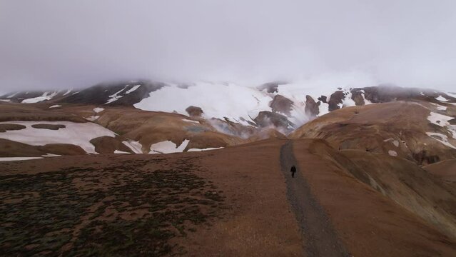 DRONE AERIAL FOOTAGE:  Tourists walking at the Kerlingarfjoll, a group of small, geothermically active, rust-colored mountains capped with snow, in Iceland's central highlands.