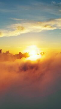 Flying above the clouds. Aerial view of clouds and sunset sun. Traveling by air perfect background. Vertical video