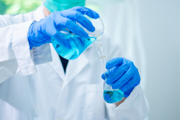 Close up of Female scientist or researcher is pouring blue substance or liquid in to a sample test tube. Concept of science, biochemistry, chemical, biotechnology laboratory. Analyzing and experiment