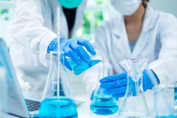 Close up of Female scientist or researcher is pouring substance or liquid in to a sample test tube. Concept of science, biochemistry, chemical, biotechnology laboratory. Analyzing and experiment