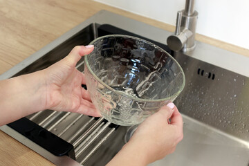 Woman washes dishes in a modern sink with a place to dry