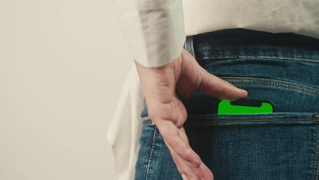 Smartphone phone with a green screen chroma key in the back pocket of jeans pants. Phone with chroma key close-up.