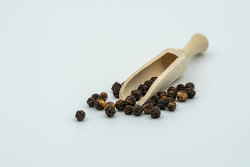 The round black pepper is placed in a small wooden spoon