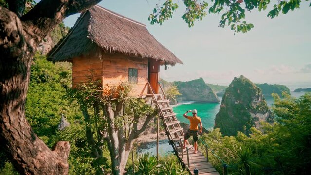 Travel people standing near scenery wooden hut on top tree and enjoy beautiful Bali destination from Thousand Islands Viewpoint on Diamond beach Bali, Indonesia 4K 