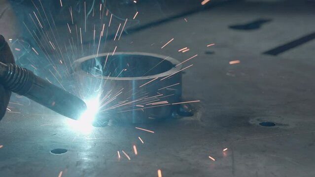 Close-up welding of metal ring to structure. Creative. Welding with sparks and special welding for metal structures. Welding sparks from melting metal