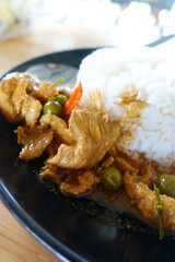 Recipe for Chicken Curry (Panang Kai) with jasmin rice in black dish on wooden table. Thai cuisine Curry with peanuts, coconut, and meat. Thai style fast food