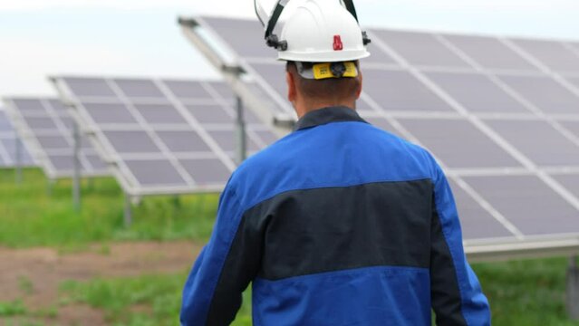 Service Engineer or electrician goes by solar panels, working and solving problem for green energy solar power plant operation. Technician maintenance solar cells on Solar Energy Plant