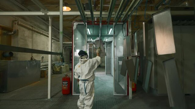 Worker pushing line of painted metal sheets into the drying chamber. Creative. Steel production plant.