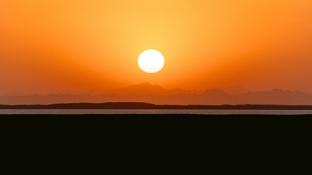 Fototapeta Epic sunset landscape sky with big bright sun going behind the mountains in Egypt.