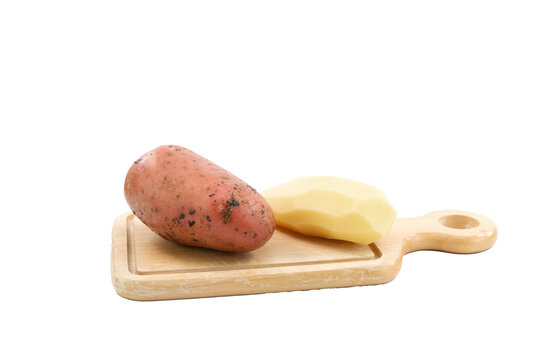 immagine primo piano di patata rossa e patata sbucciata su tagliere in legno, vista dall'alto su sfondo trasparente