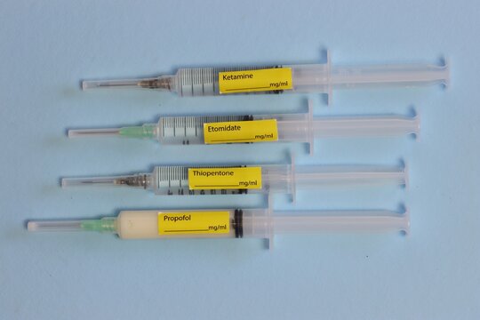 Different types of hypnotic drugs in a syringe with labels in a light blue background 