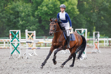 Young woman horseback riding on her show jumping course