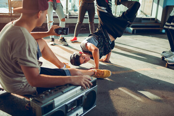 Group of young people break dancing in a parking lot and recording with their smart phone