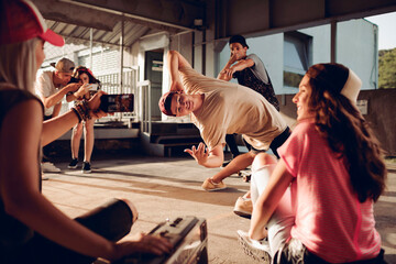 Fototapeta na wymiar Group of young people break dancing in a parking lot and recording with their smart phone