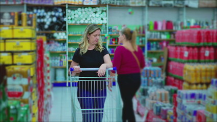 Woman pushing shopping cart at Grocery Store aisle browsing products on display depicting consumerism lifestyle habits