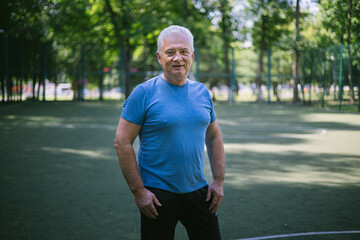 portrait of a senior man over 50 with gray hair in a sports jersey on a sports court