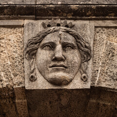 An architectural element of an old building. Stone bas-relief of the head of an ancient deity.