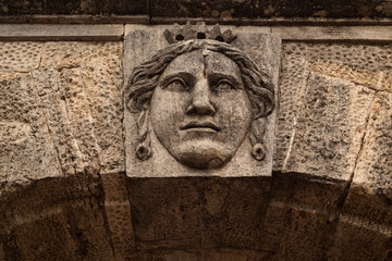 An architectural element of an old building. Stone bas-relief of the head of an ancient deity.