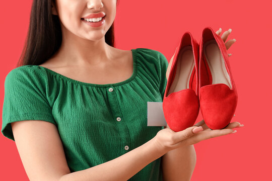 Female seller with stylish shoes on red background, closeup