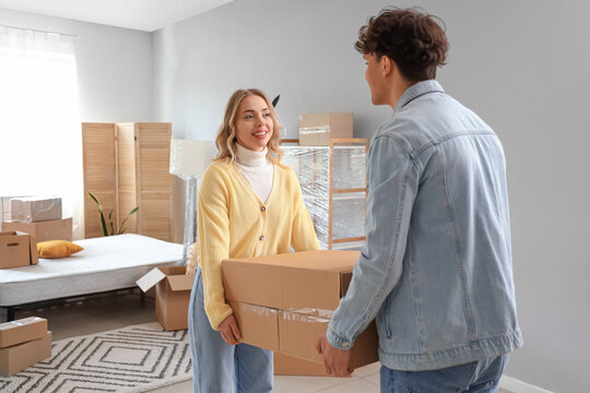 Young couple carrying box in bedroom on moving day - Powered by Adobe