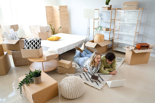 Young couple using laptop in bedroom on moving day - Powered by Adobe