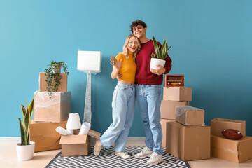 Happy young couple with keys from their new flat in room on moving day
