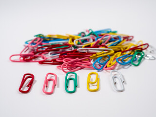 Multicolored paper clips on a white background. Colored paper clips close up.