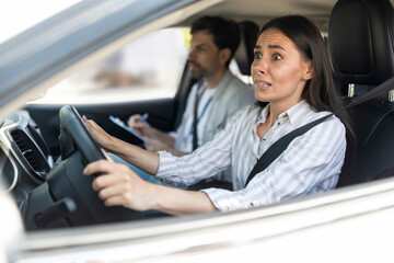 Scared unconfident woman driving car with instructor by her side