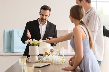 Male wedding planner working with couple in office