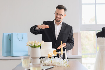 Male wedding planner with cake in office