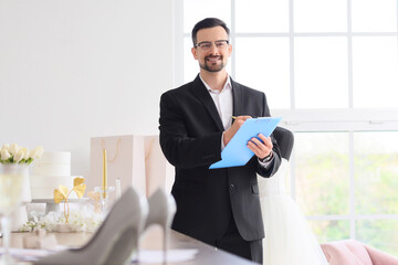 Male wedding planner working with clipboard in office