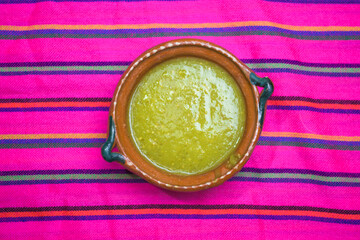 Mexican green sauce in a clay plate on a colorful tablecloth. mexican food concept