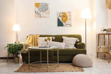 Interior of stylish living room with cozy green sofa, coffee table and glowing lamps