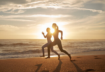 Positive energy millennial caucasian twins sisters women running, enjoy workout at sea beach, sun flare - obrazy, fototapety, plakaty