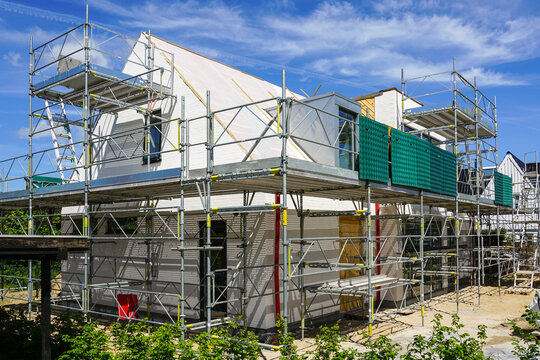 An unfinished modern single-family residential house, surrounded by scaffolding