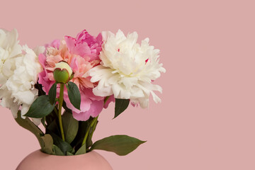 Vase of peonies on pink background, closeup