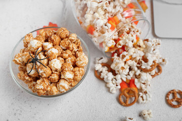 Bowl with tasty caramel popcorn and spider on light background, closeup. Halloween celebration