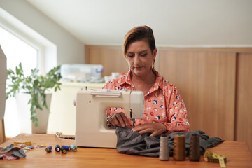Serious mature seamstress using sewing machine