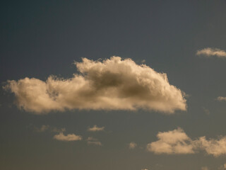 Single fluffy cloud over sunset sky background. Fluffy cumulus cloud shape photo