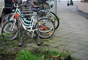 Fahrradständer mit vielen Fahrrädern auf Gehweg in Großstadt am Nachmittag im Sommer